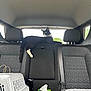 cat, tuxedo_cat, backseat, car_interior, headrest, seatbelt, pet_carrier, tissue_box, rear_window, upholstery, tail, paw, relaxed, looking_out, black_and_white, road_trip, vehicle, cozy, center_seat, interior_accessory