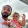 man, baby, child, person, outdoor, cloudy_sky, house, building, facial_expression, beard, pink_clothing, minnie_mouse, cute, holding, portrait, casual, fun, family, human, smile