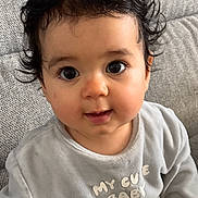 Luc a rejoint le concours — aidez-le/la à gagner de superbes lots ! baby, child, cute, plush_toy, hedgehog_toy, gray_outfit, couch, indoor, portrait, curly_hair, dark_hair, big_eyes, smiling, seated, soft_lighting, blue_wall, cozy, comfortable, casual_clothing, infant