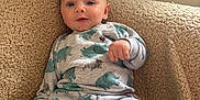 Jasper is registered to the contest to win money with this photo: baby, infant, pajamas, elephant_pattern, blanket, beige, cozy, cute, child, portrait, indoor, smile, face, young, sitting, clothing, soft, comfort, relaxed, home