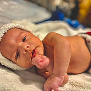 Axel is registered to the contest to win money with this photo: baby, infant, newborn, santa_hat, blanket, bed, portrait, cute, cozy, hand, eyes, mouth, bokeh, indoor, holiday, christmas, soft_texture, skin, sleepy, warm_lighting