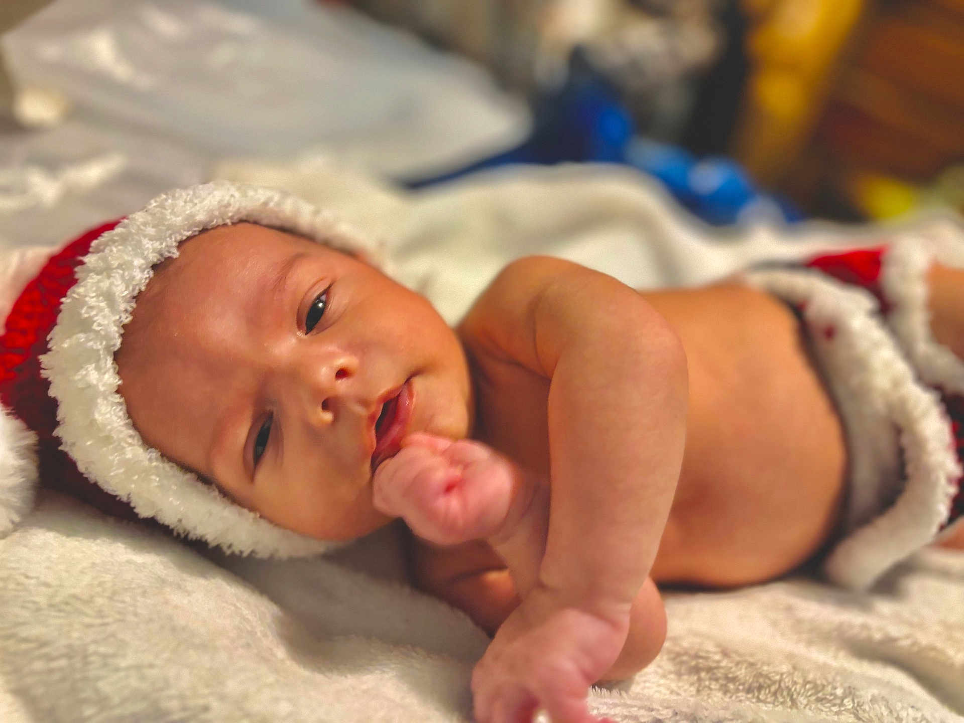 Axel is registered to the contest to win money with this photo: baby, infant, newborn, santa_hat, blanket, bed, portrait, cute, cozy, hand, eyes, mouth, bokeh, indoor, holiday, christmas, soft_texture, skin, sleepy, warm_lighting