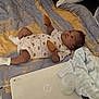 baby, infant, bed, blanket, pillow, laptop, bottle, mittens, clothing, sleepwear, person, indoor, resting, soft, cozy, newborn, cute, lying_down, carpet, technology