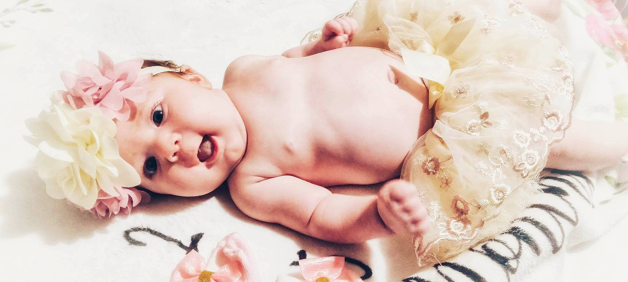 Piper is registered to the contest to win money with this photo: abdomen, arm, baby, baby_toddler_clothing, chest, child, eyelash, finger, happy, headgear, headpiece, human_body, leg, person, pink, product, skin, textile, toddler, toy