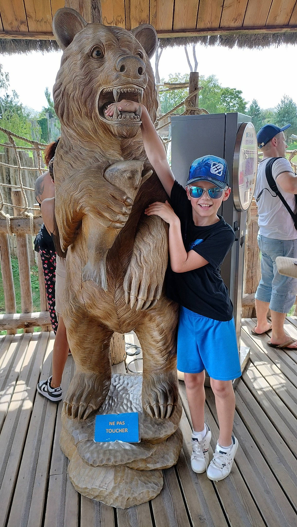 Louméo a rejoint le concours — aidez-le/la à gagner de superbes lots ! art, artifact, baseball_cap, brown_bear, chainsaw_carving, fun, hat, headwear, joy, leisure, nonbuilding_structure, person, recreation, sculpture, shoe, shorts, sky, statue, sunglasses, terrestrial_animal