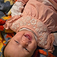 Rosalie joined the competition — help win amazing prizes! baby, child, smiling, pink_dress, embroidery, blanket, hand, lying_down, happy, indoor, close_up, infant, cute, soft_texture, colorful, person, face, portrait, toddler, warm