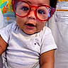 Seth Williams is registered to the contest to win money with this photo: animal_print, baby, child, closeup, colorful_background, curly_hair, cute, face, giraffe, glasses, happy, indoors, infant, onesie, playful, portrait, red_glasses, seated, smiling, young