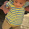 boy, cap, casual_clothing, child, concrete_ground, cute, daylight, gold_necklace, hands_supporting, outdoor, portrait, shadow, shorts, smiling_face, sneakers, striped_shirt, sunlight, toddler, walking, young_child