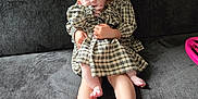 Olivia is registered to the contest to win money with this photo: baby, child, sibling, couch, plaid_dress, indoor, family, hug, cute, blond_hair, foot, smile, person, home, toddler, hair_bow, seated, cozy, affection, portrait