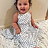 baby, barefoot, bedroom, blanket, child, close_up, curly_hair, fashion, fluffy_blanket, hair_clip, happy, indoors, polka_dot_dress, portrait, sitting, smiling, toddler, wall, white_dress, wood_floor