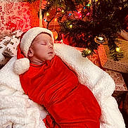 Ryker is registered to the contest to win money with this photo: baby, christmas, christmas_tree, cozy, decorations, festive, gifts, holiday, indoor, infant, newborn, ornaments, portrait, red_swaddle, santa_hat, sleeping, soft_textures, string_lights, white_blanket, wrapped_presents
