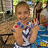child, girl, smile, face, hands, rings, colorful, birthday, table, tablecloth, outdoor, party, decoration, chair, people, hair, clothing, nature, celebration, happy