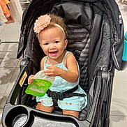Aniyah joined the competition — help win amazing prizes! toddler, smiling, flower_headband, stroller, child, blue_dress, indoor, shopping, clothing_rack, happy, seat_belt, toy_or_snack_pouch, retail, floor_tile, person, baby, cute, hair, cart, store