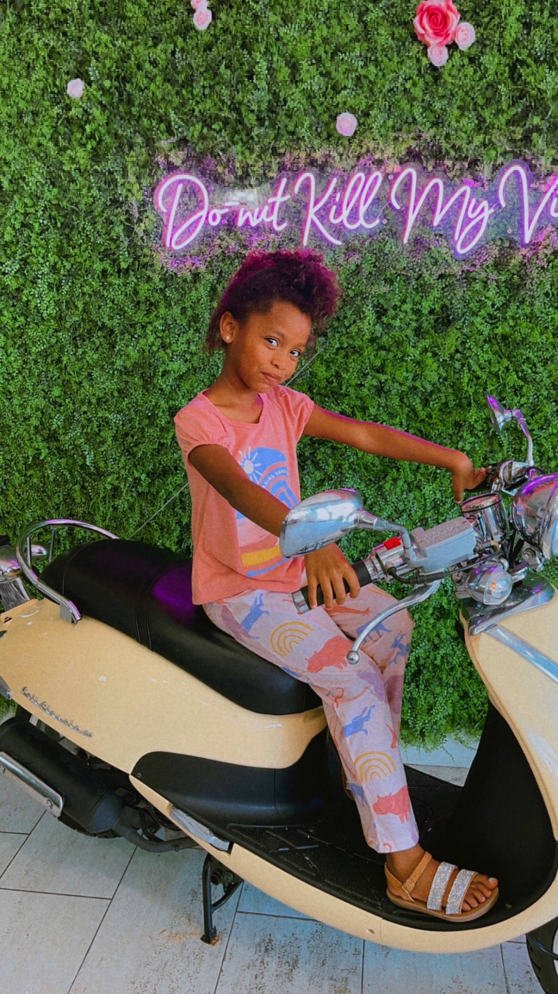 Amani is registered to the contest to win money with this photo: automotive_design, automotive_exterior, automotive_wheel_system, font, fun, grass, happy, human_leg, landscape, leg, leisure, magenta, motor_vehicle, person, pink, plant, recreation, rolling, scooter, sitting