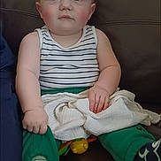 Brandon Lee Jnr joined the competition — help win amazing prizes! toddler, child, baby, striped_tank_top, green_pants, blanket, socks, couch, leather, indoor, rosy_cheeks, blue_eyes, toy, seated, clothing, person, face, hand, footwear, home