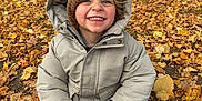 Tyler participe au concours pour gagner de l'argent avec cette photo : autumn, casual_clothing, child, cool_weather, daylight, fall_leaves, happy, hat, jacket, leaves, nature, outdoor, park, person, portrait, seasonal, sitting, smiling, trees, young_child