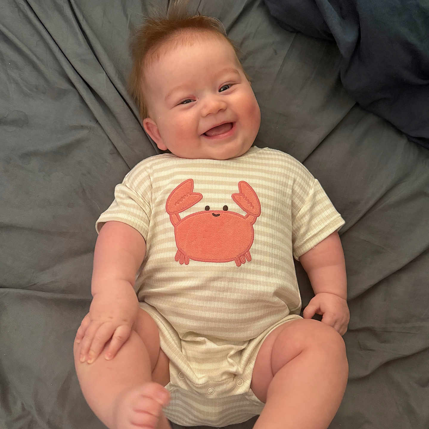 Kaos joined the competition — help win amazing prizes! baby, infant, smiling, happy, onesie, striped_clothing, crab_graphic, lying_down, blanket, soft_fabric, cute, toddler, child, skin, face, expression, hair, indoors, person, playful