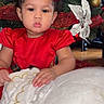 toddler, child, red_dress, curly_hair, red_bows, christmas_tree, holiday_decorations, plush_toy, indoor, festive, cute, portrait, holiday, celebration, face, hands, floor, decor, young_child, expression