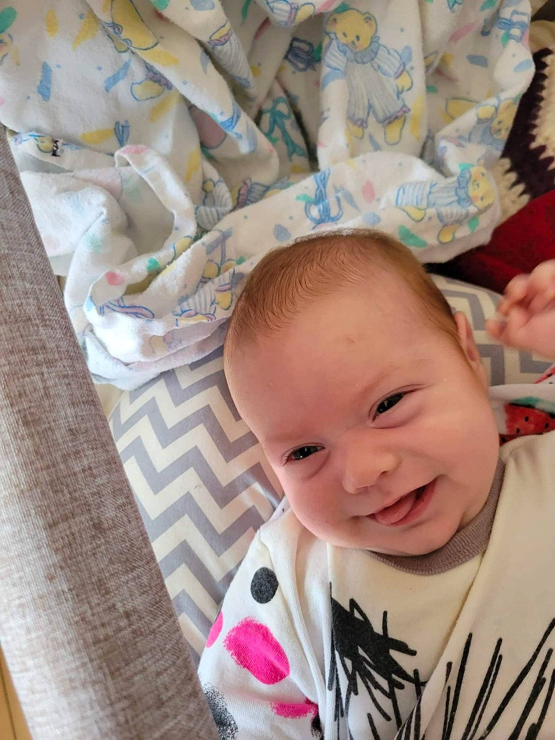 Evanah participe au concours pour gagner de l'argent avec cette photo : baby, baby_products, baby_toddler_clothing, cheek, child, comfort, eyelash, face, happy, head, linens, pattern, person, room, skin, sleeve, smile, textile, toddler, white