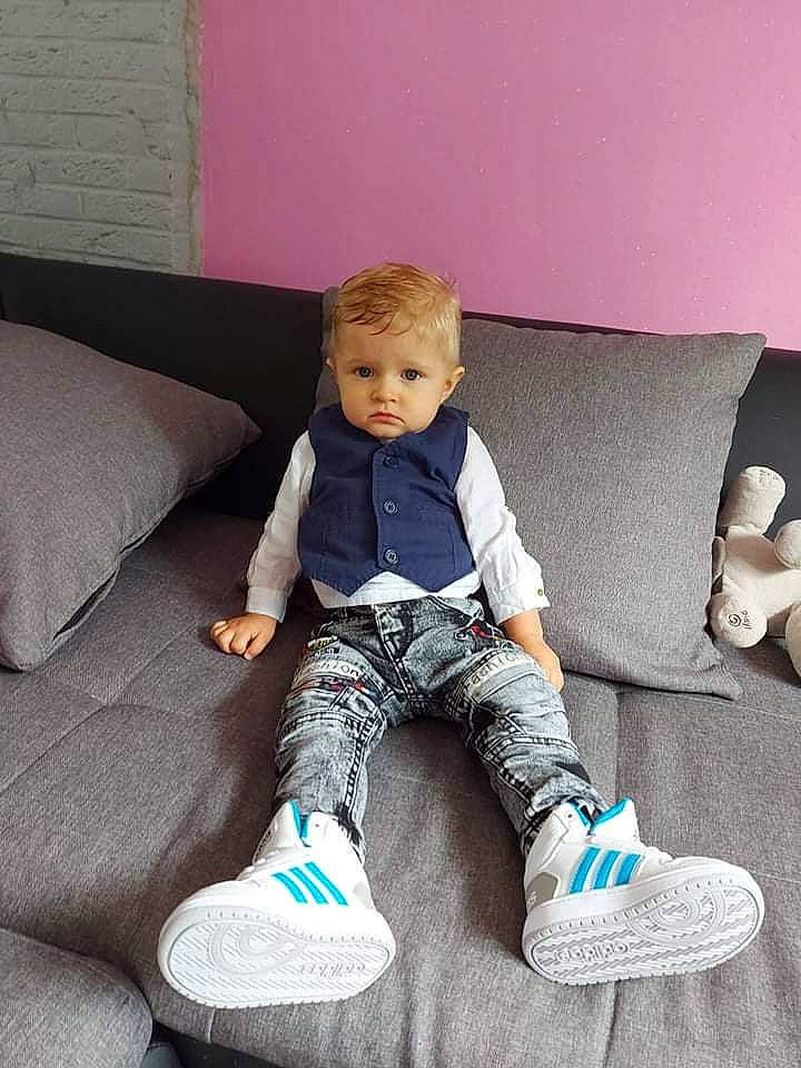 Dorian participe au concours pour gagner de l'argent avec cette photo : baby_toddler_clothing, comfort, couch, face, flooring, footwear, furniture, hair, head, knee, leg, person, purple, rectangle, shoe, sleeve, sneakers, sportswear, thigh, toddler