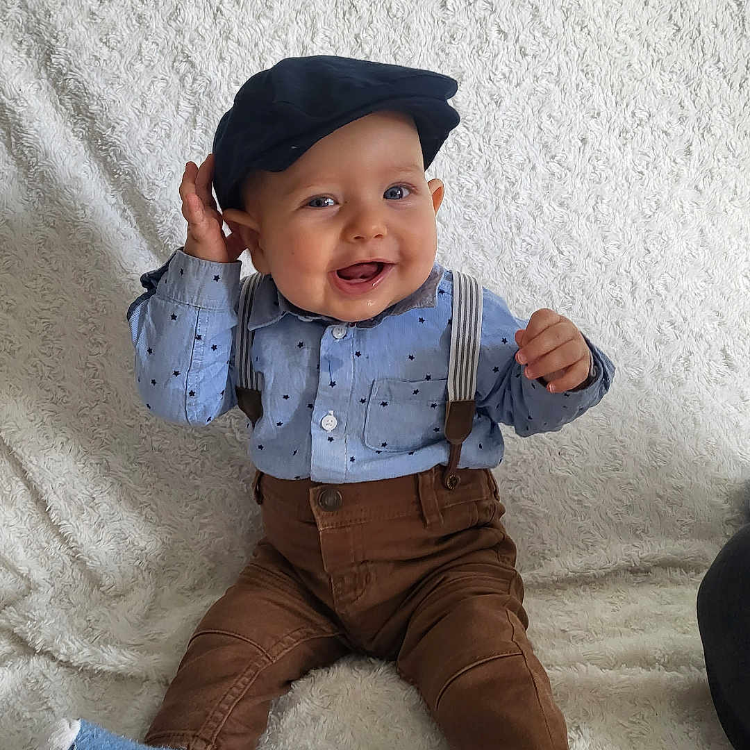 Naël participe au concours pour gagner de l'argent avec cette photo : baby, bodypart, clothing, couch, cutlery, face, finger, fork, furniture, hand, happy, hat, head, pants, person, photography, portrait, sitting, smile, spoon