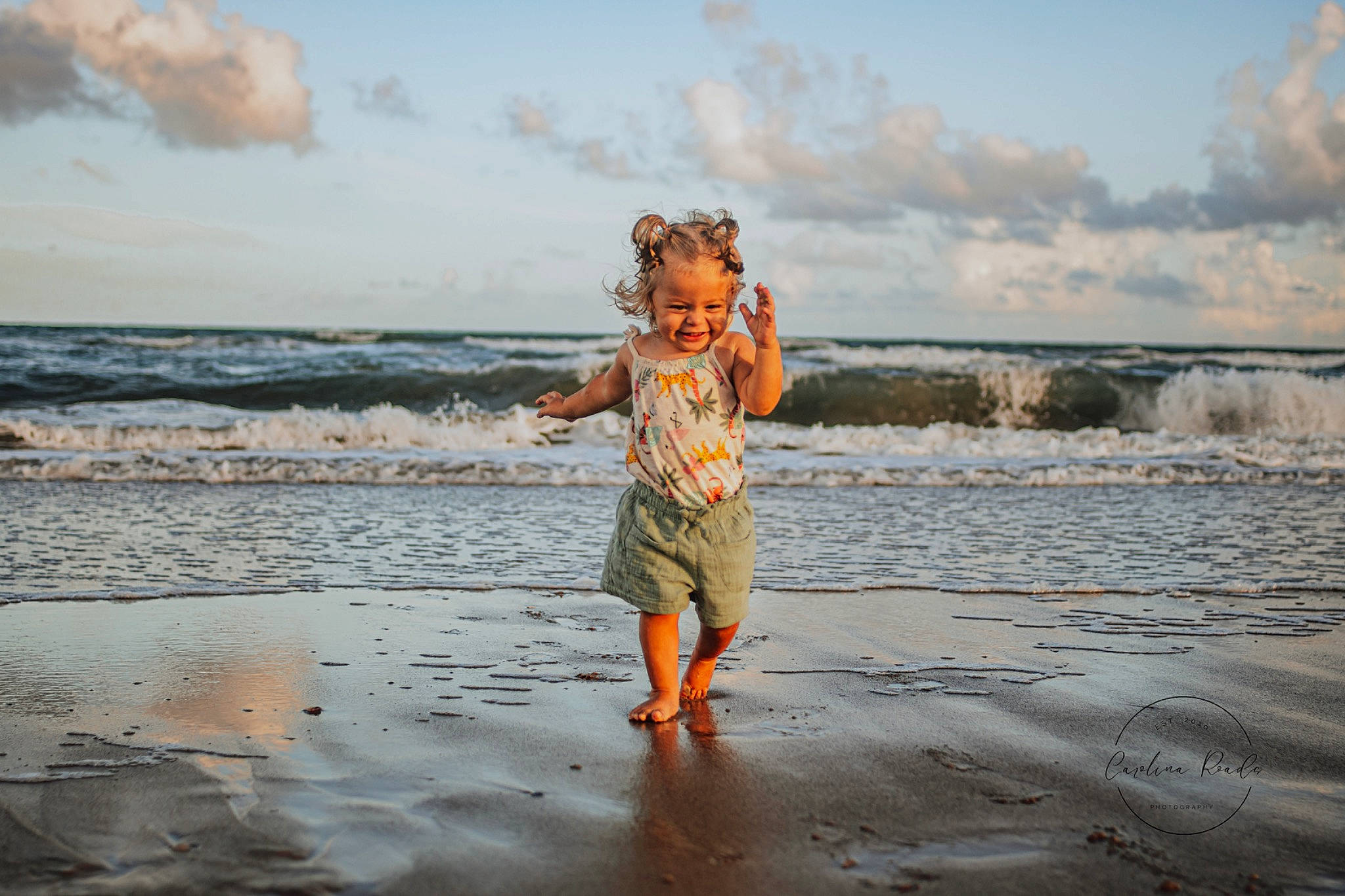 Sophie is registered to the contest to win money with this photo: beach, cloud, coastal_and_oceanic_landforms, flash_photography, fun, gesture, happy, horizon, joy, landscape, leisure, natural_environment, people_in_nature, people_on_beach, person, sky, smile, standing, sunlight, toddler