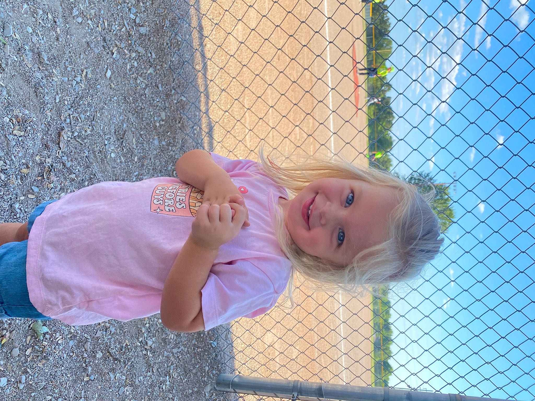 Sophie is registered to the contest to win money with this photo: baby_toddler_clothing, chain_link_fencing, child, clothing, cloud, electric_blue, fence, fun, grass, happy, joy, leisure, magenta, mesh, net, pattern, person, sky, smile, toddler
