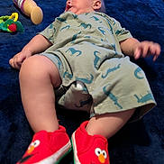 Isaac joined the competition — help win amazing prizes! baby, bed, blanket, blue_blanket, child, chubby, cute, dinosaur_print, elmo, footwear, indoor, infant, lotion_bottle, lying_down, person, red_shoes, relaxed, romper, sleepy, toy