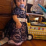 Naomi joined the competition — help win amazing prizes! toddler, child, dress, lace, pacifier, toy, school_bus, floor, wooden_floor, furniture, curtains, indoor, person, baby_bottle, hand, face, hair, window, light, playing