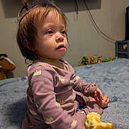 Naomi is registered to the contest to win money with this photo: apple, bed, blanket, child, clothing, face, foot, furniture, hair, hand, home, indoor, pajamas, person, room, sitting, skin, television, toddler, toy