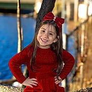 Maria Alice is registered to the contest to win money with this photo: child, girl, red_dress, headband, bow, smile, long_hair, outdoor, tree, nature, portrait, happy, posing, confident, young, cute, fashion, winter_clothing, hands_on_hips, background_blur