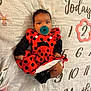 baby, infant, pacifier, red_dress, ladybug_pattern, black_socks, blanket, floral_pattern, numbers, months_marker, cute, lying_down, indoors, child, portrait, clothing, baby_girl, soft_lighting, close_up, adorable