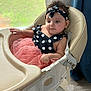 baby, high_chair, polka_dot, pink_skirt, headband, curly_hair, indoor, window, natural_light, child, cute, infant, seated, clothing, portrait, young_child, furniture, looking_away, skin, earrings