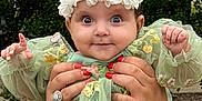 Simon joined the competition — help win amazing prizes! baby, child, face, flower_headband, green_dress, hands, nail_polish, outdoor, garden, curly_hair, embroidery, cute, wide_eyes, person, portrait, infant, holding, expression, nature, smiling