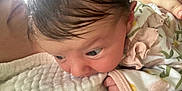 Annalise joined the competition — help win amazing prizes! baby, infant, close_up, face, hand, blanket, texture, hair, clothing, floral_pattern, curious, nibbling, soft, indoor, person, skin, cute, newborn, eyes, resting
