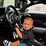 Kingsley participe au concours pour gagner de l'argent avec cette photo : toddler, child, car_interior, bmw, steering_wheel, black_clothing, shorts, sneakers, white_socks, bracelet, leather_seat, curious, sitting, young_child, portrait, car, vehicle, indoor, seat, hands_on_wheel