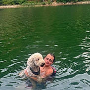 Dexter is registered to the contest to win money with this photo: person, dog, water, lake, swimming, nature, greenery, trees, outdoor, summer, pet, animal, companion, happy, relaxation, reflection, ripples, friendship, canine, leisure