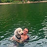 person, dog, water, lake, swimming, nature, greenery, trees, outdoor, summer, pet, animal, companion, happy, relaxation, reflection, ripples, friendship, canine, leisure