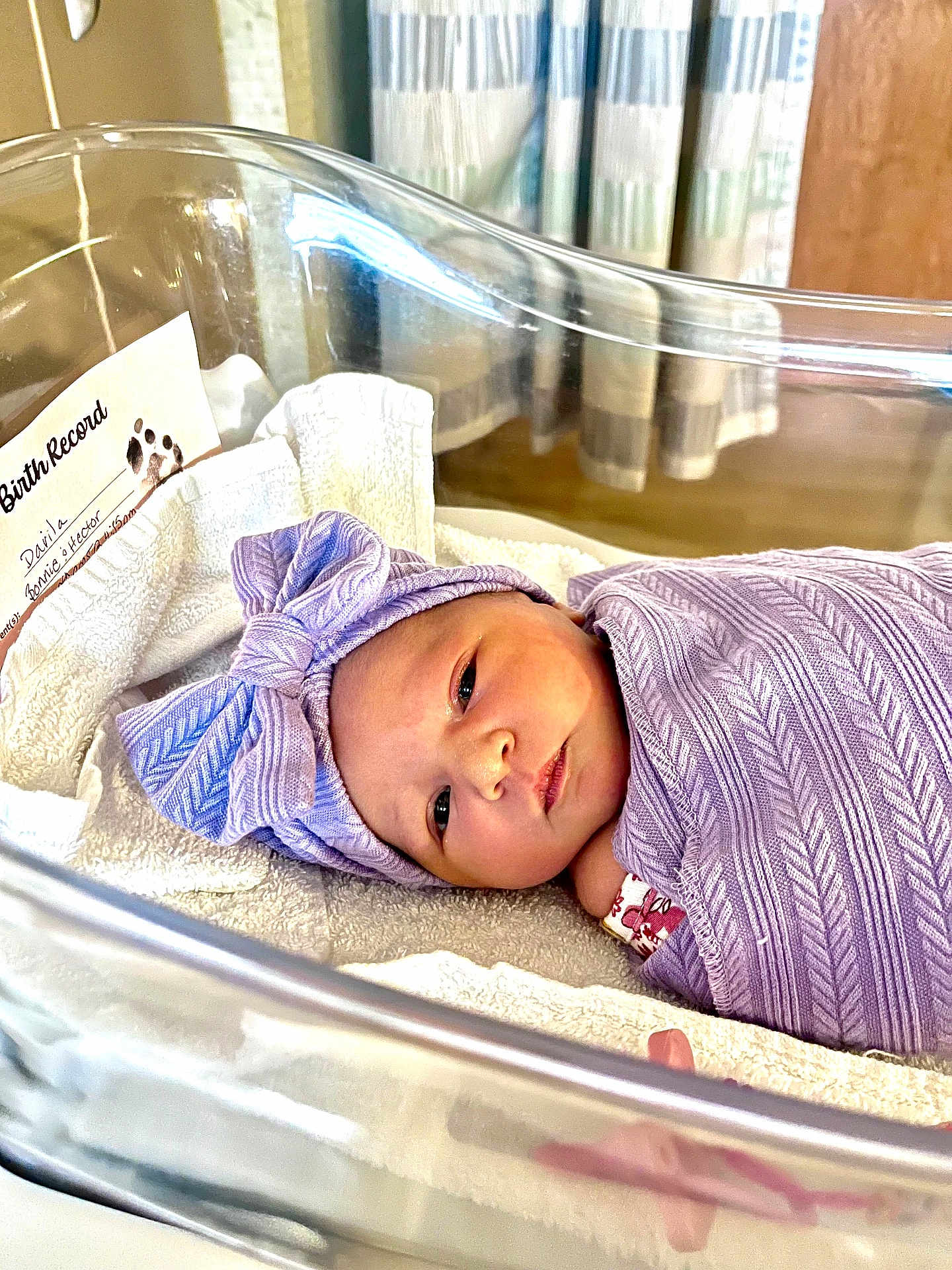 Liliana joined the competition — help win amazing prizes! newborn, baby, hospital, bassinet, blanket, headband, purple, wrapped, infant, sleeping, birth_record, towel, face, cute, person, indoors, lying_down, peaceful, swaddled, newborn_baby