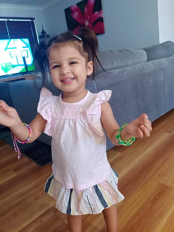 Aisha is registered to the contest to win money with this photo: baby_toddler_clothing, child, couch, day_dress, display_device, flat_panel_display, floor, flooring, happy, hardwood, joy, laminate_flooring, living_room, person, pink, skin, studio_couch, television, toddler, varnish