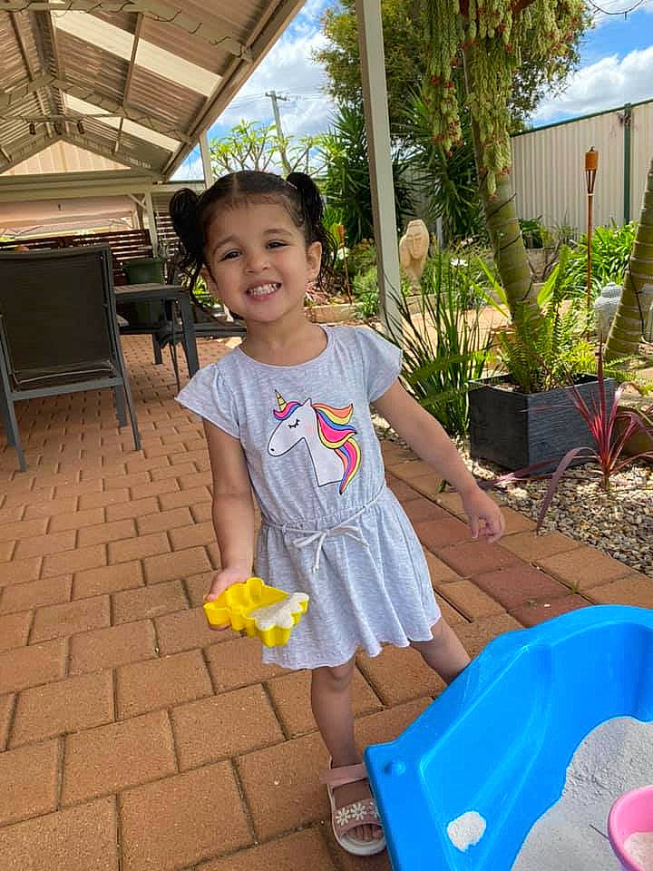 Aisha is registered to the contest to win money with this photo: baby_toddler_clothing, backyard, child, day_dress, dress, flowerpot, garden, joy, one_piece_garment, person, pink, plastic, sandal, summer, toddler, yard