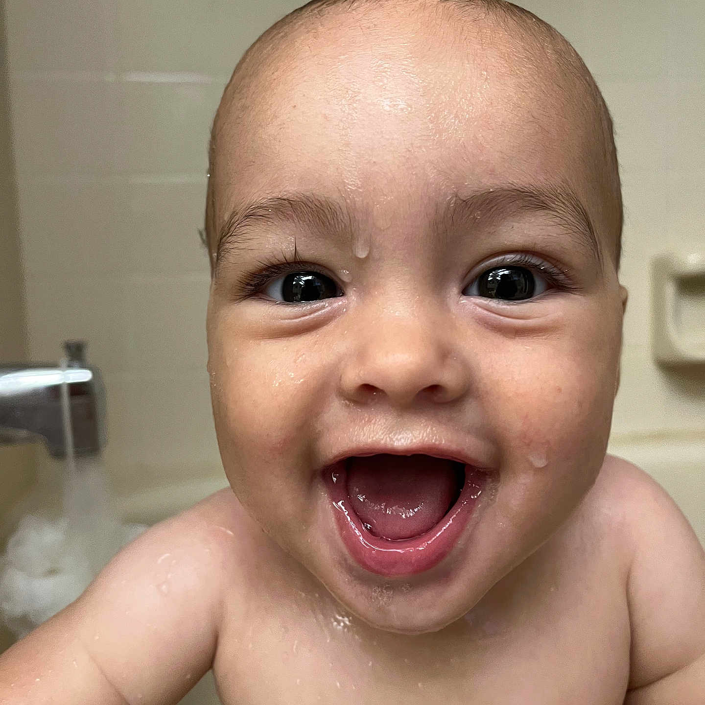 Uriyah is registered to the contest to win money with this photo: baby, bath, bathtub, child, closeup, cute, expression, eyes, face, happy, infant, innocence, joy, mouth_open, person, skin, smile, tiled_wall, water, wet_skin