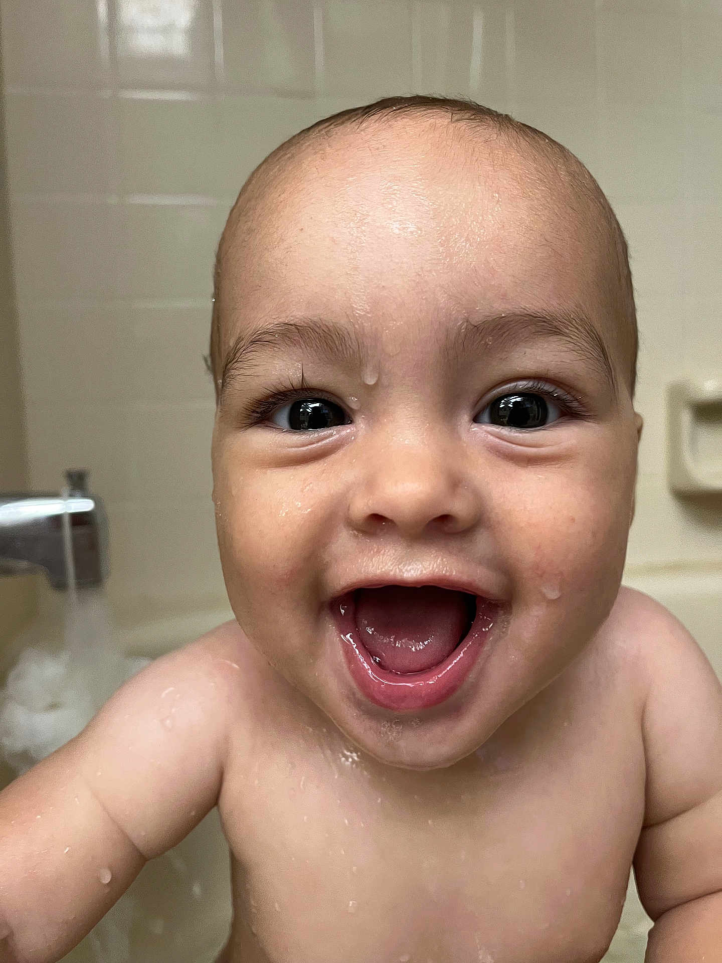 Uriyah is registered to the contest to win money with this photo: baby, child, bath, water, wet_skin, smile, happy, face, closeup, tiled_wall, bathtub, joy, innocence, skin, mouth_open, eyes, expression, person, infant, cute