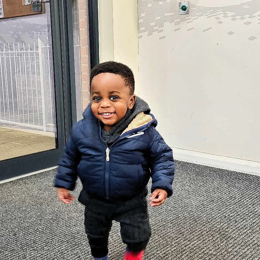 Jevin is registered to the contest to win money with this photo: boy, child, clothing, coat, door, face, footwear, happy, head, jacket, jeans, male, pants, person, photography, portrait, shoe, sitting, sneaker, standing