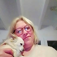 Estella participe au concours pour gagner de l'argent avec cette photo : woman, glasses, dog, indoor, blonde_hair, pet, holding, smile, face, closeup, ring, sweater, cozy, portrait, home, small_dog, affection, cute, person, light