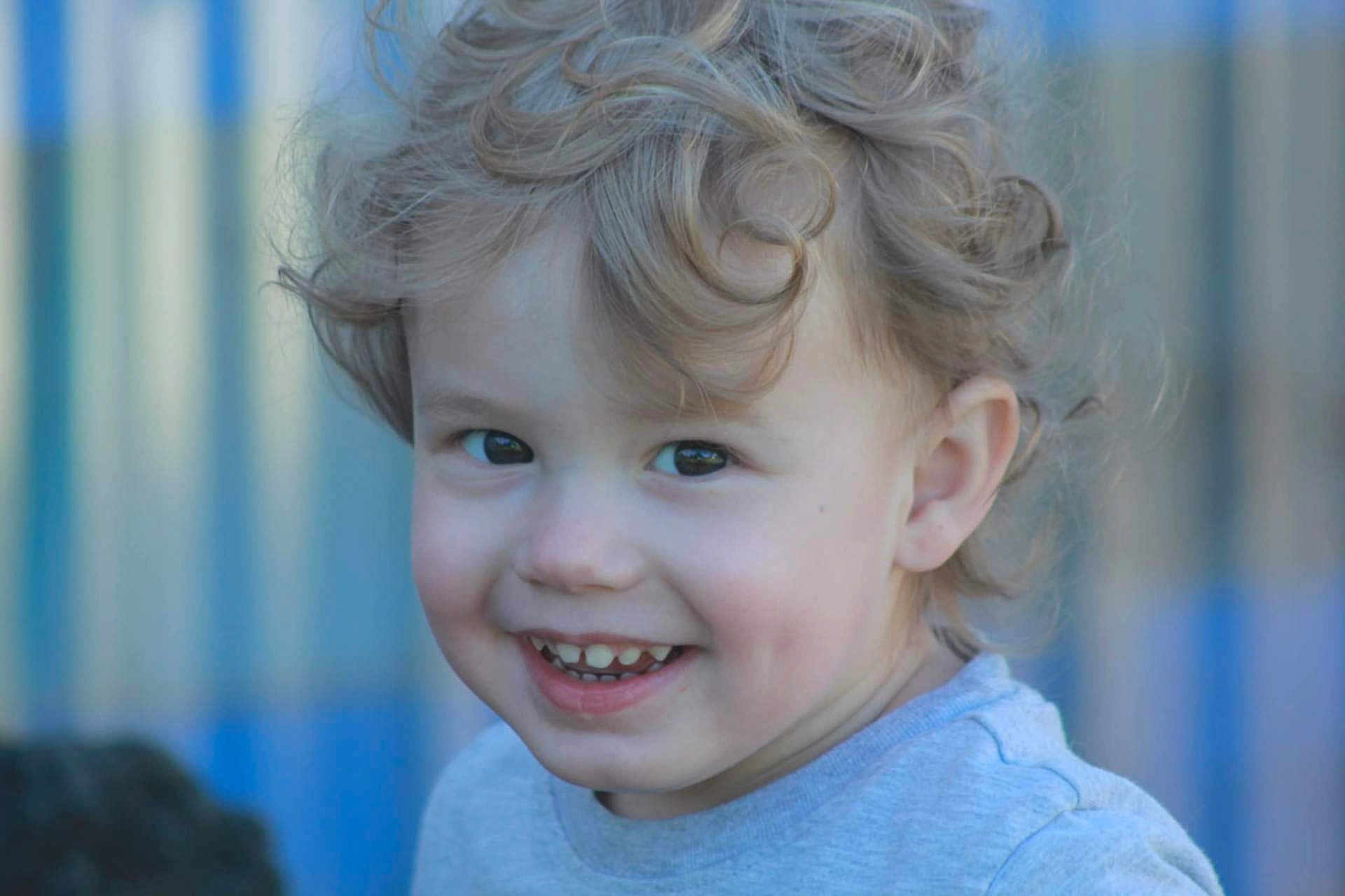 Dasan joined the competition — help win amazing prizes! child, toddler, curly_hair, smile, happy, face, portrait, closeup, blue_background, casual_clothing, cute, young, person, innocent, outdoor, natural_light, cheerful, skin, head, expression