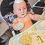 baby, birthday, cake, celebration, child, curious, cute, face, food, frosting, hand, hat, high_chair, indoor, messy, person, seat, smudged, table, toddler
