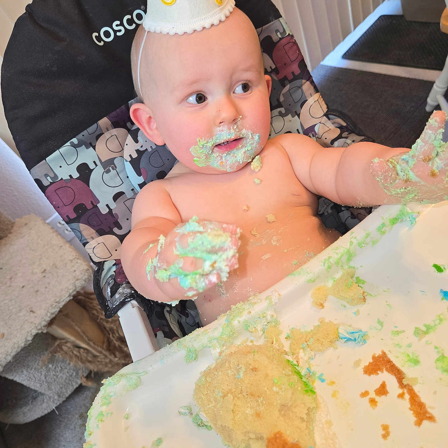 Oliver is registered to the contest to win money with this photo: baby, birthday, cake, celebration, child, curious, cute, face, food, frosting, hand, hat, high_chair, indoor, messy, person, seat, smudged, table, toddler