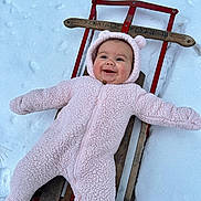 Dayana joined the competition — help win amazing prizes! baby, child, cold_weather, cozy, cute, face, fun, happy, infant, outdoor, person, pink_onesie, play, sled, smiling, snow, toy, warm_clothing, winter, wood