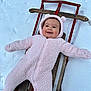 baby, child, cold_weather, cozy, cute, face, fun, happy, infant, outdoor, person, pink_onesie, play, sled, smiling, snow, toy, warm_clothing, winter, wood